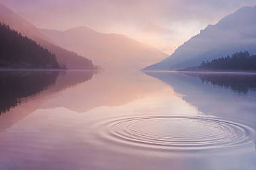 Lac de montagne au lever du jour, eau calme et cercles à la surface