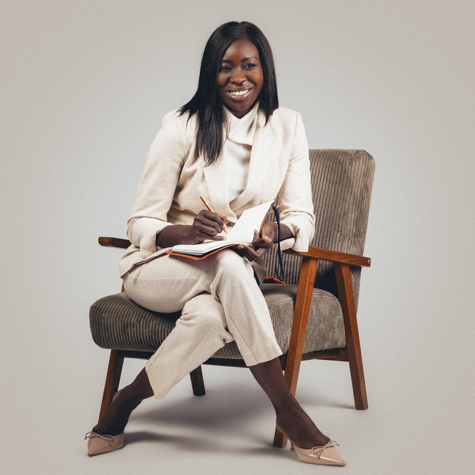 Thioro Loum, souriante, prend des notes dans un carnet, assise dans un fauteuil